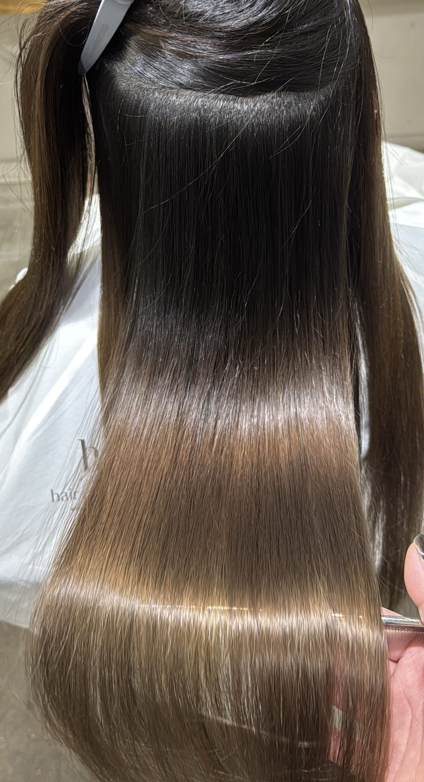 ブリーチ履歴のあるロングヘアを分けて内側まで縮毛矯正後の艶を確認している状態