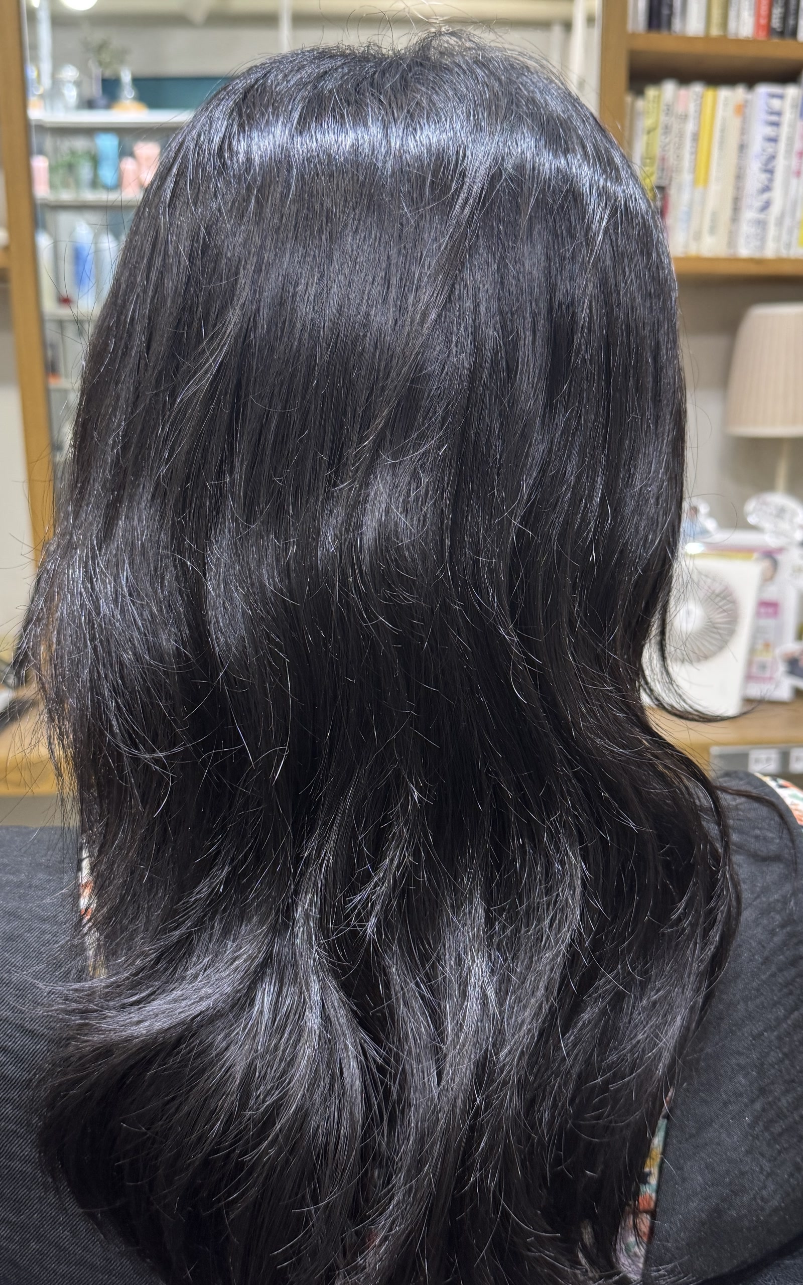 縮毛矯正前の後ろ姿で、髪全体の膨らみと毛先のうねりが見える状態